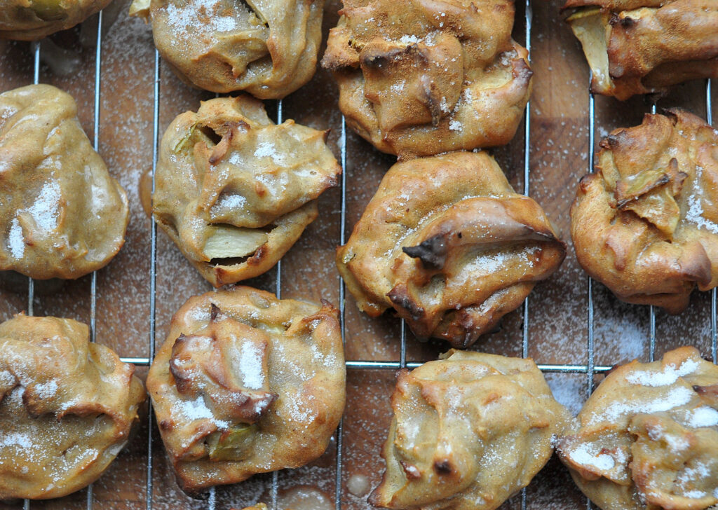 apple cider puffs resting on a cooling rack with wooden background