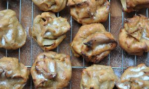 apple cider puffs resting on a cooling rack with wooden background