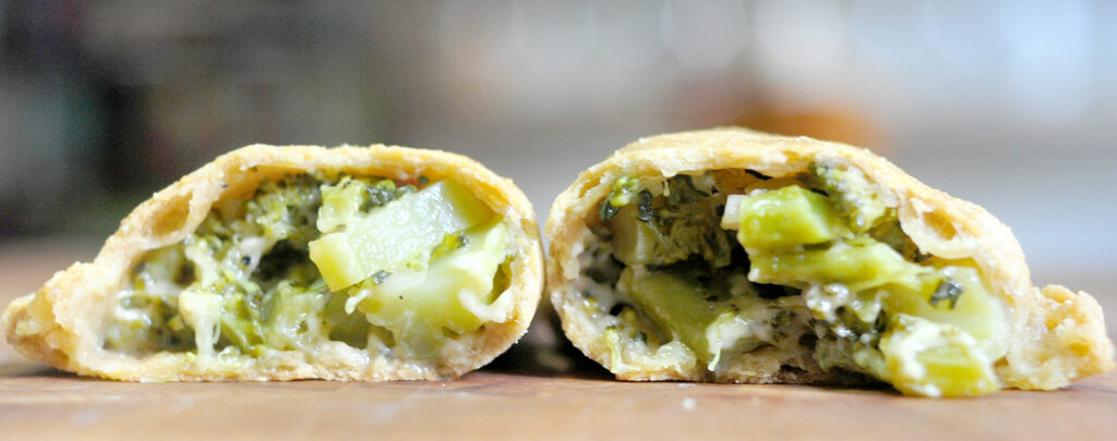 cross section of an empanada filled with broccoli and cheddar