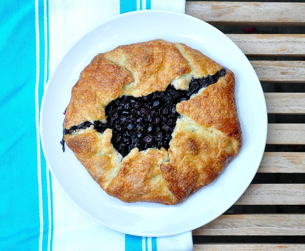 blueberry crostata on a white plate with blue striped dish towel