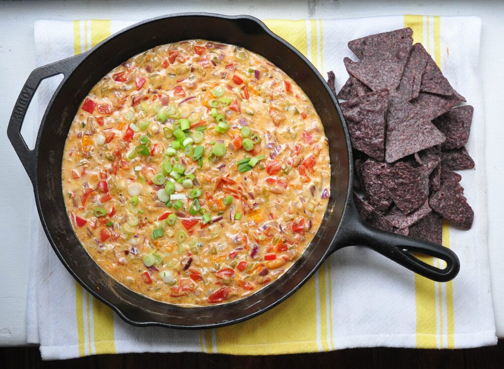 queso fundido in a cast iron pan with tortilla chips on the side