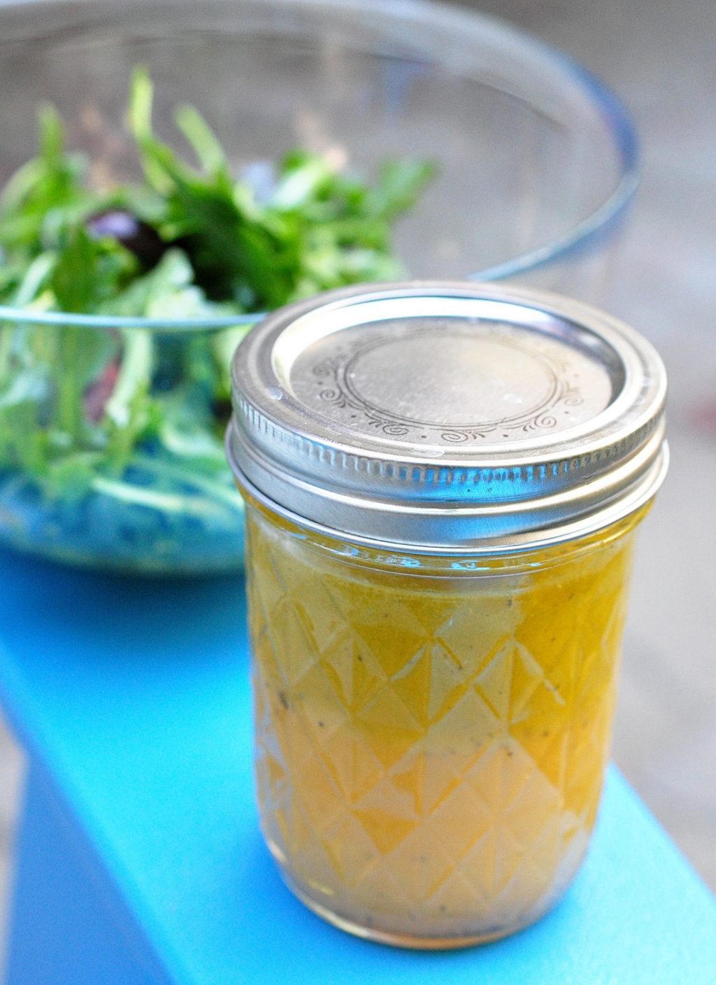 jar of triple citrus dressing with salad in background
