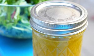 jar of triple citrus dressing with salad in background