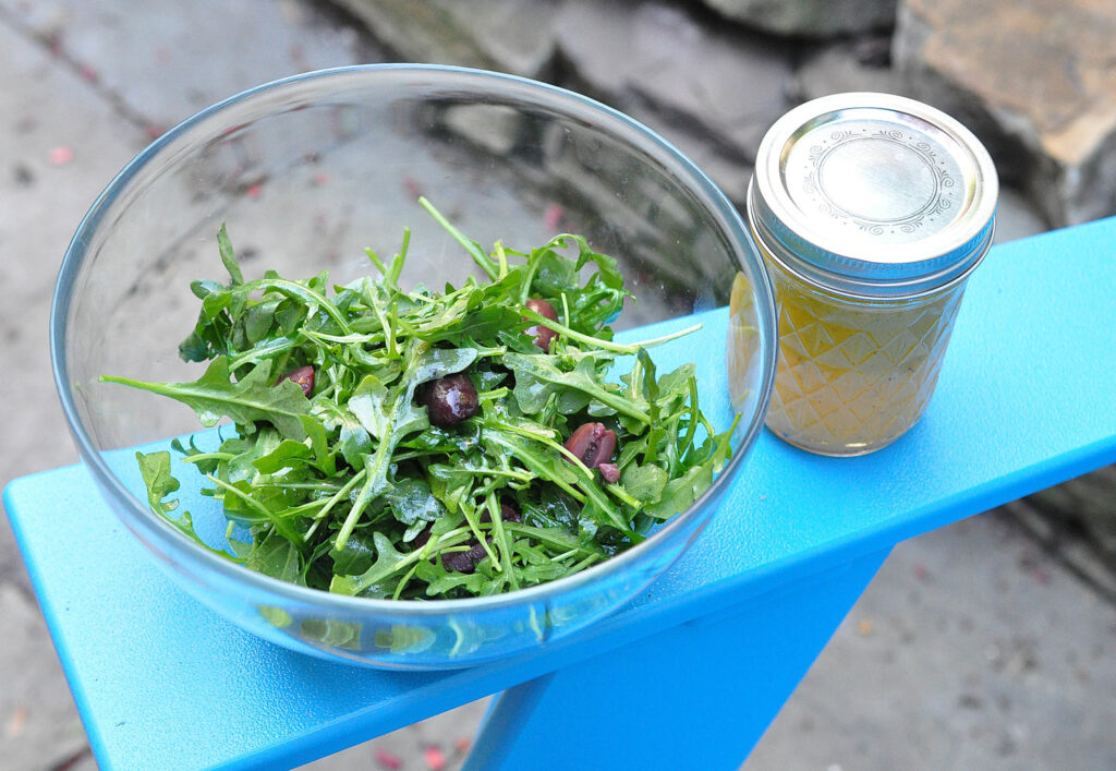 salad in foreground with jar of lemon, orange and lime dressing