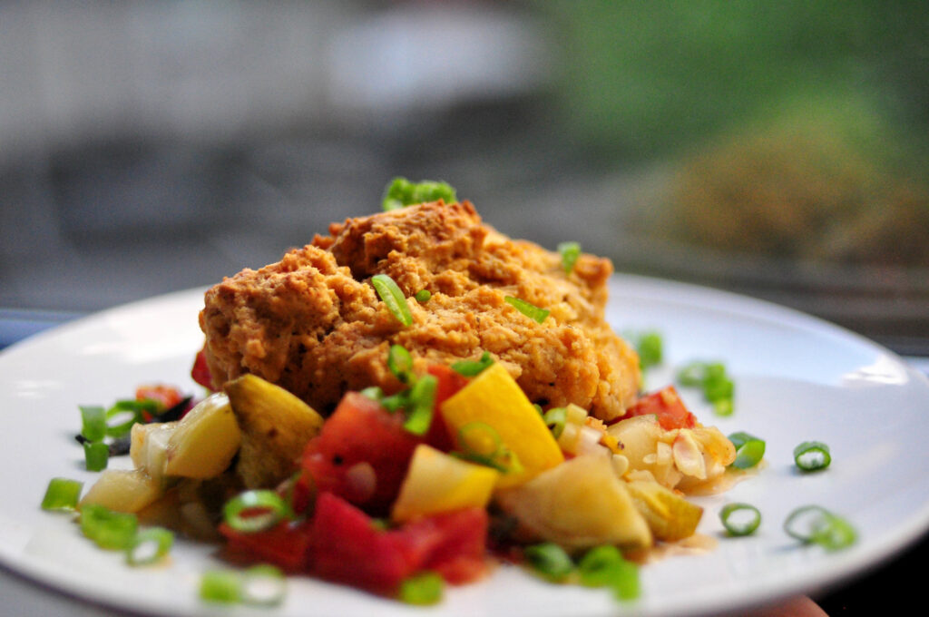 zucchini and tomato savory summer cobbler on a white plate