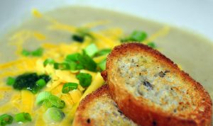 cauliflower soup topped with cheddar and scallions with sliced baguette