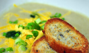 cauliflower soup topped with cheddar and scallions with sliced baguette