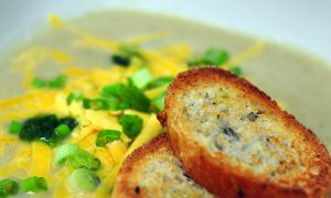 cauliflower soup topped with cheddar and scallions with sliced baguette