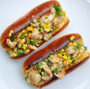 2 overstuffed hot dog rolls full of shrimp, corn and vegetables