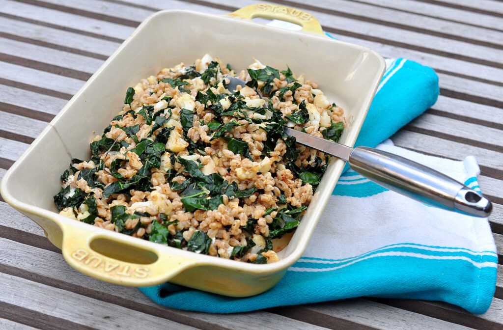 platter of farro salad with cauliflower and kale on dish towel with serving spoon