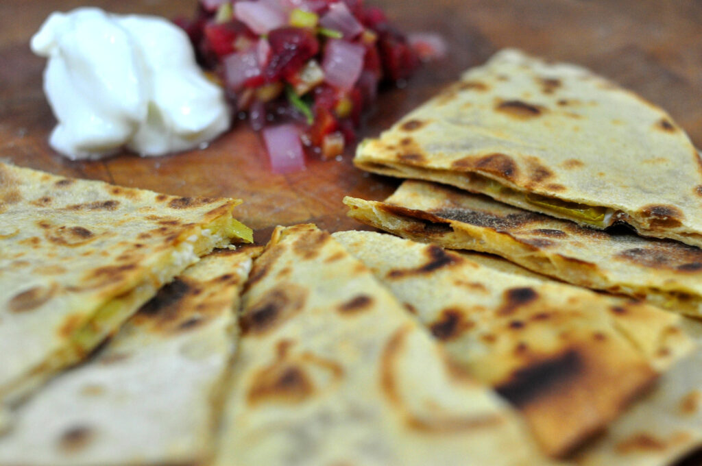 green chile and cheddar quesadillas cut into triangles and served with salsa and sour cream