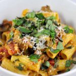 eggplant tomato pasta piled in a bowl and topped with cheese and basil