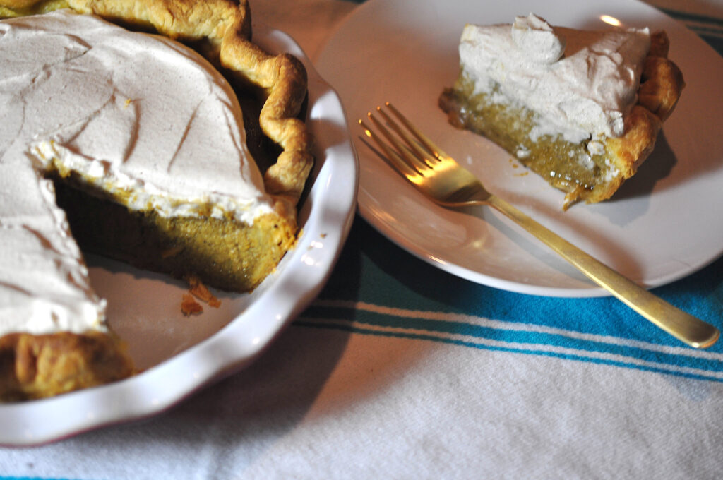 Pumpkin pie with a slice removed and a gold fork