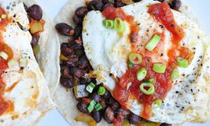 tortillas topped with beans, a fried egg, salsa and scallions