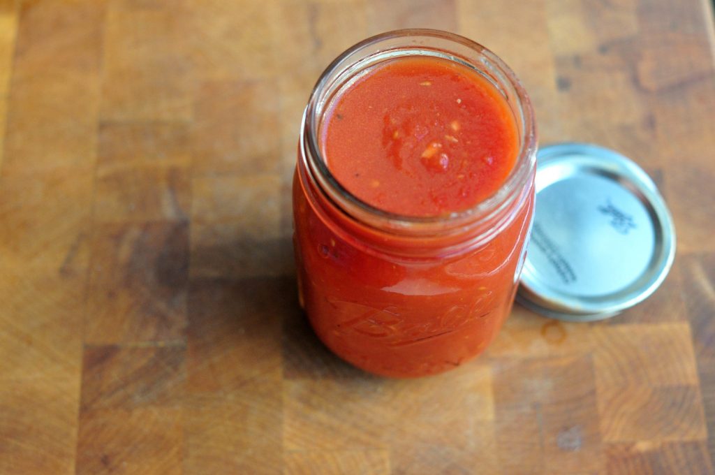 small jar of tomato sauce on wooden board
