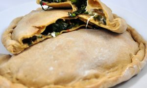 broccoli rabe calzone cut in half laying on top of another calzone