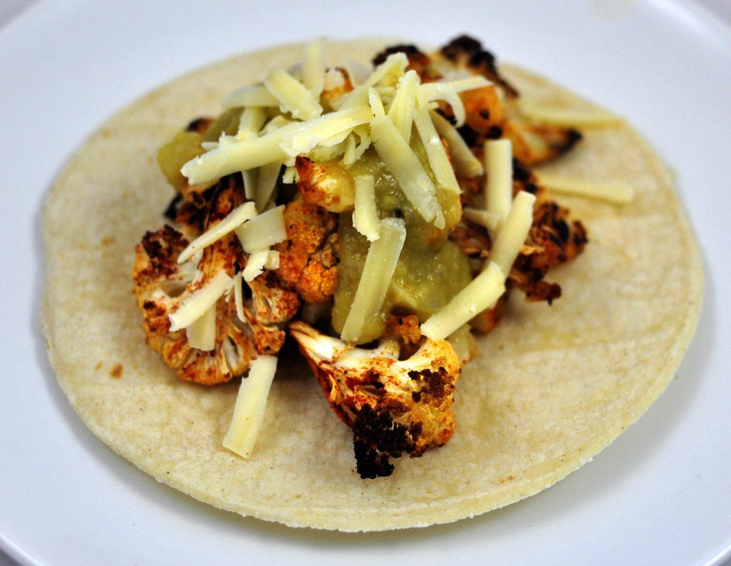 cauliflower tacos with roasted cauliflower rubbed with smoked paprika and topped with cheese and green salsa
