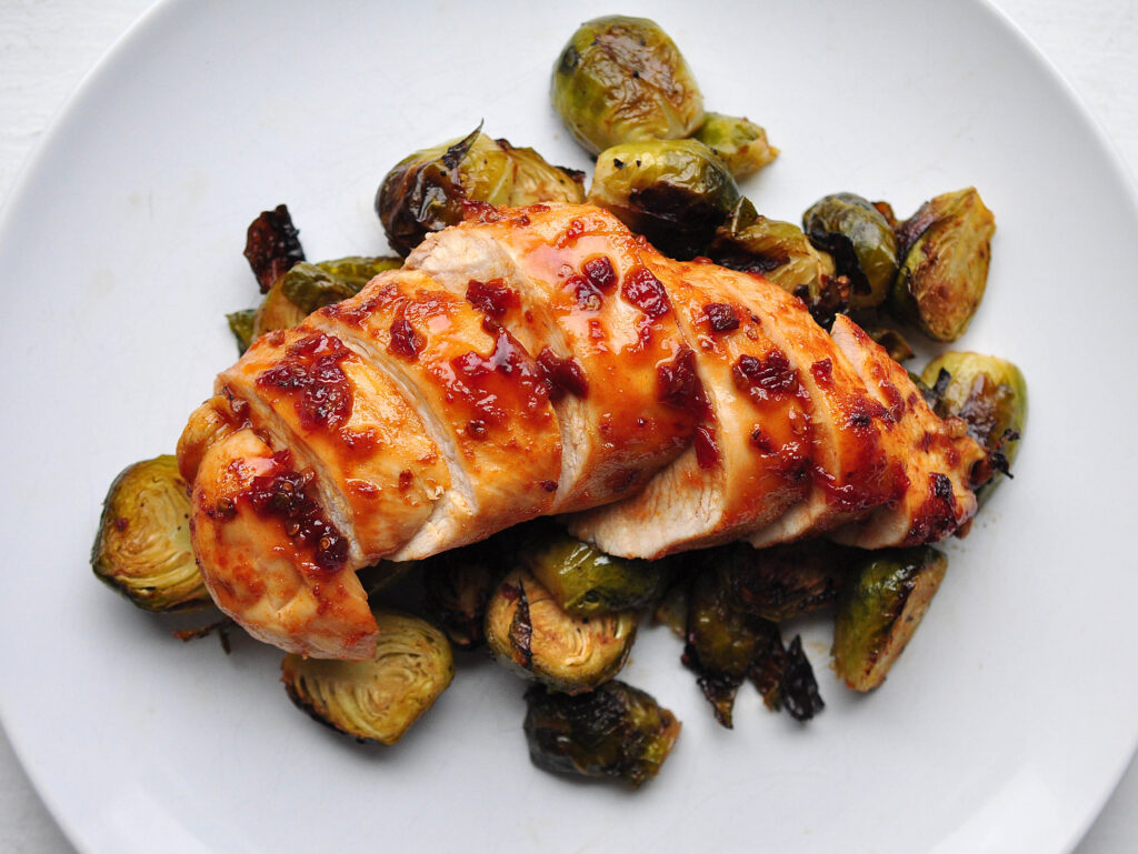 chipotle honey chicken on a bed of brussels sprouts on a white plate