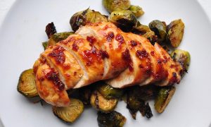 chipotle honey chicken on a bed of brussels sprouts on a white plate