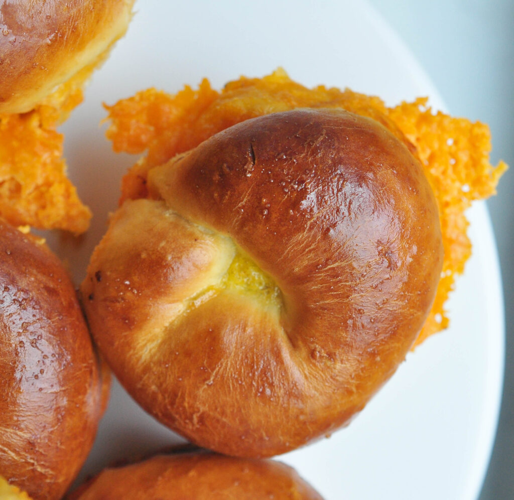 cheese bun with crispy cheese flowing out of the side on a white background