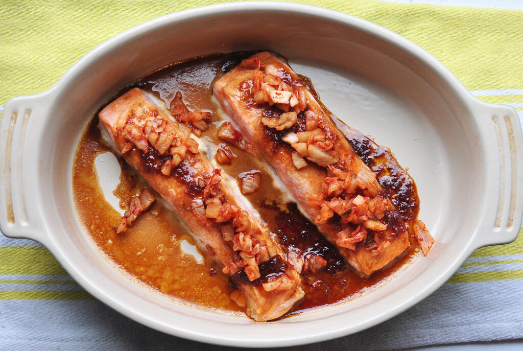 two salmon fillets glazed with garlic and soy sauce and topped with chopped kimchi