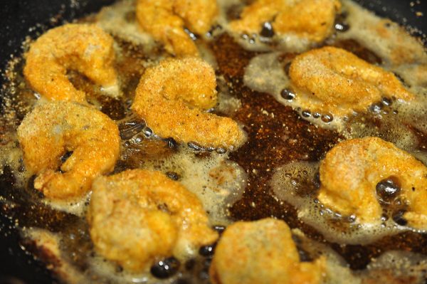 shrimp frying in a pan before flipping to fry second side