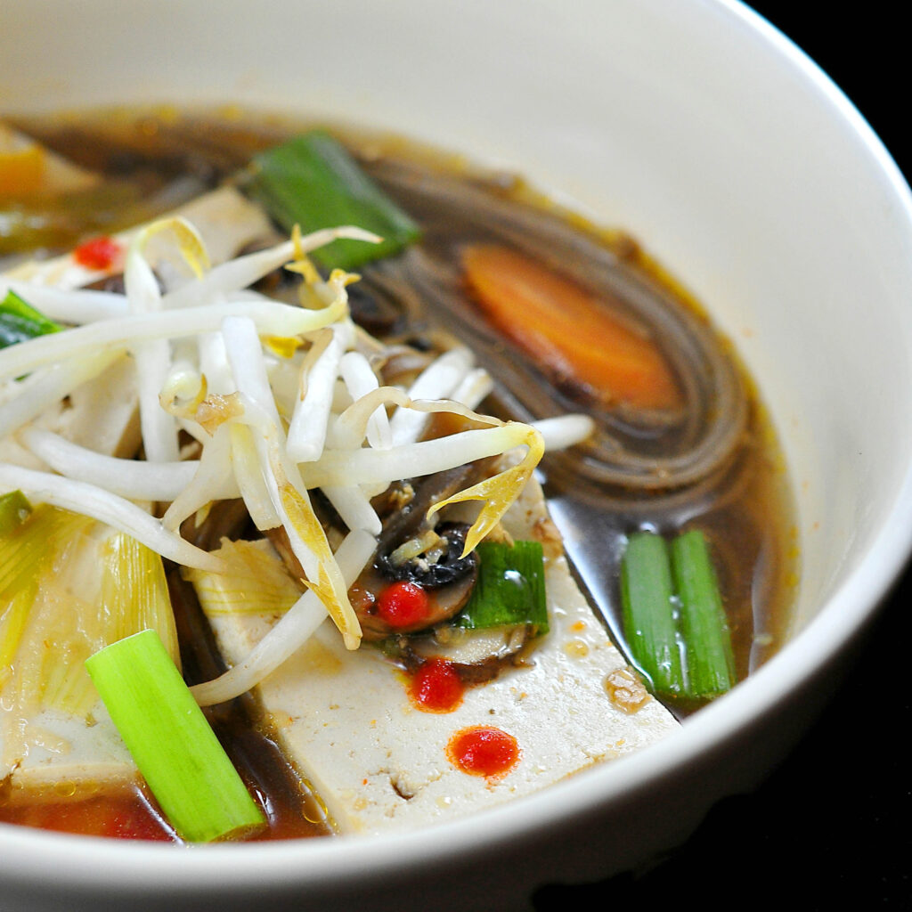 Tofu hot pot, bowl of noodles, tofu and vegetables in a warm ginger-garlic broth