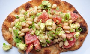 naan bread piled high with avocado, white bean and grapefruit salad
