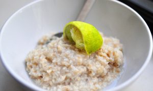 coconut lime oatmeal in a white bowl with a squeezed lime wedge on top