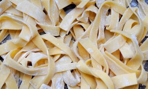 uncooked fresh pasta noodles in a pile tossed with flour