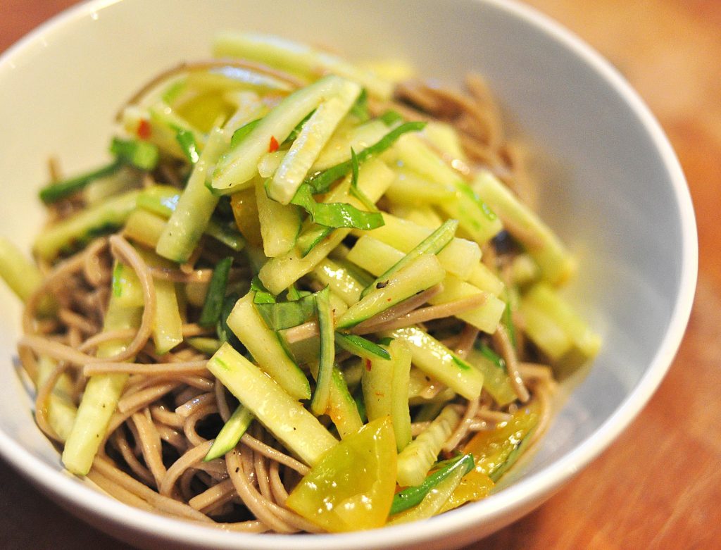 white bowl with Asian Noodle salad of soba noodles, cucumber shreds, basil and tomato