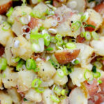 close up of potato salad with lots of scallions and bits of black pepper