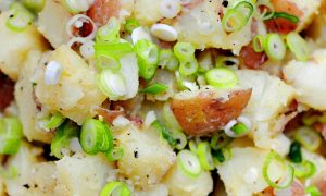 close up of potato salad with lots of scallions and bits of black pepper