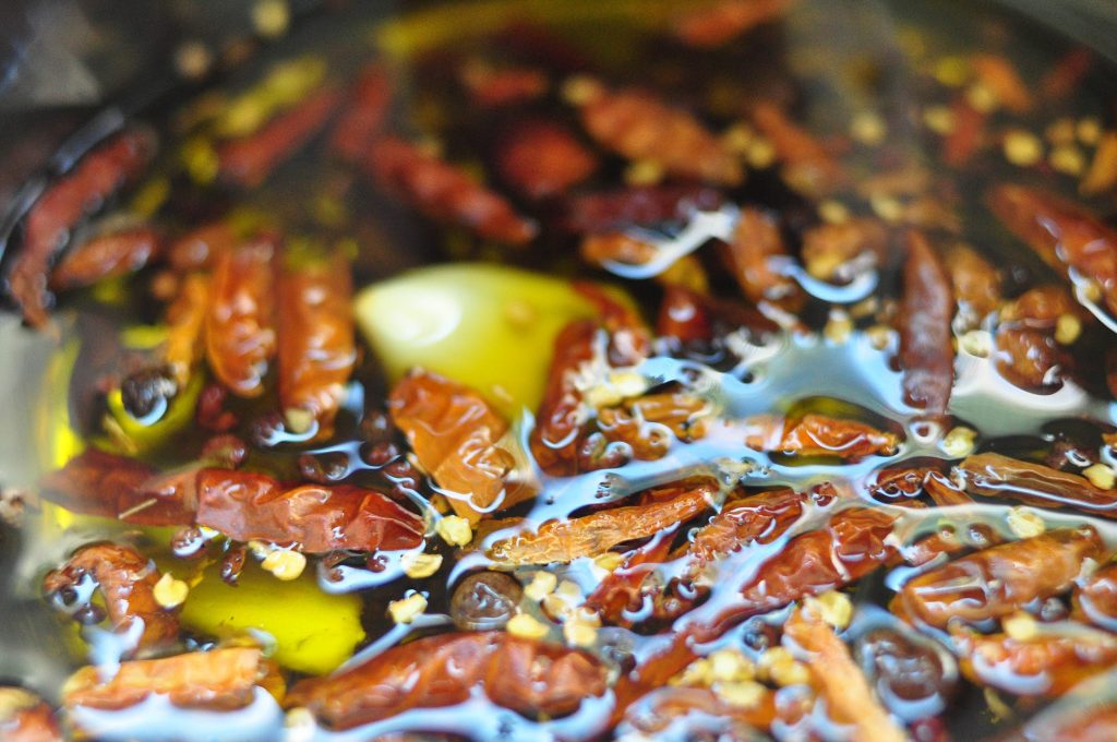 close up of chiles, garlic and spices infusing into oil