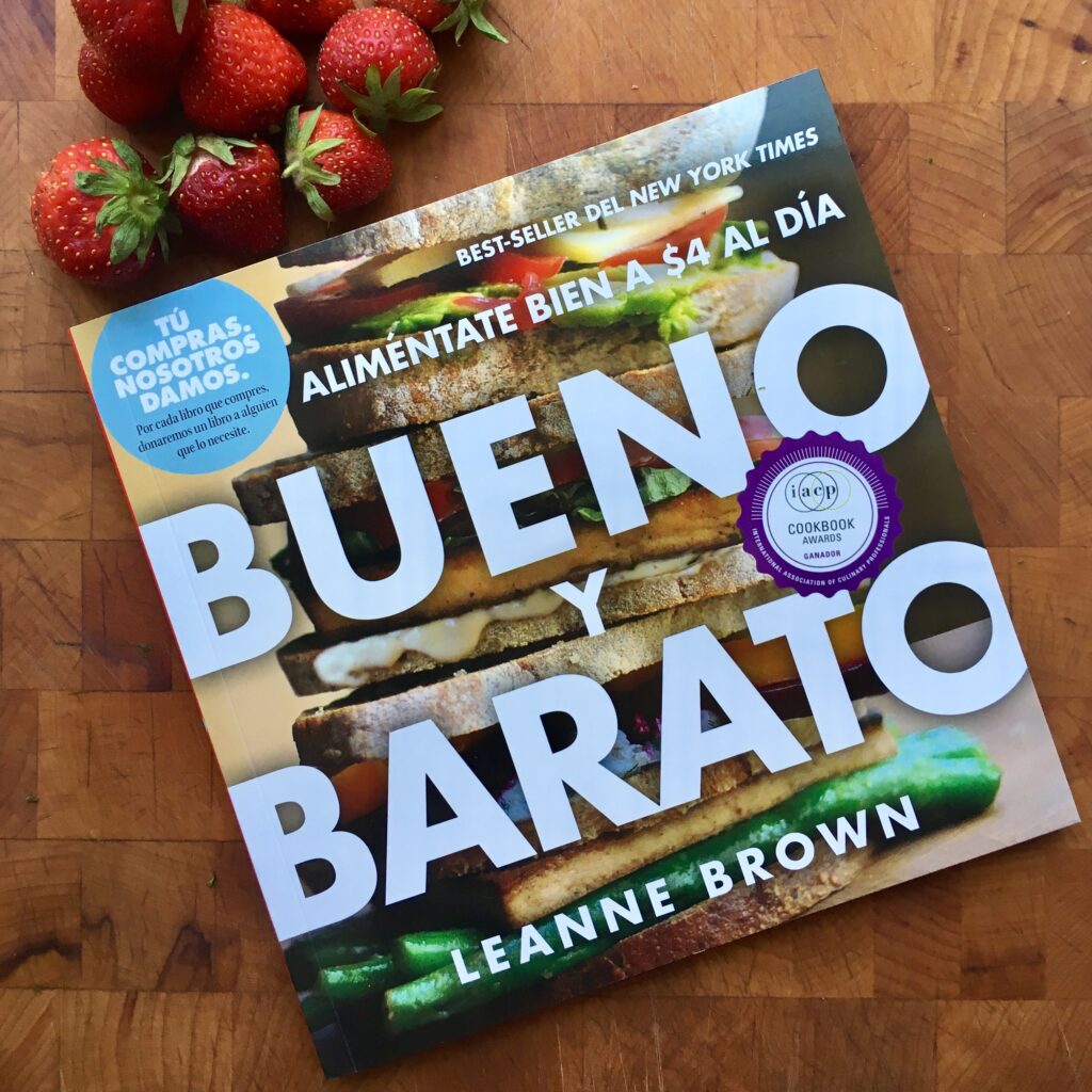 copy of Bueno Y Barato book with strawberries on a wood block background