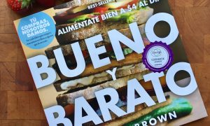 copy of Bueno Y Barato book with strawberries on a wood block background
